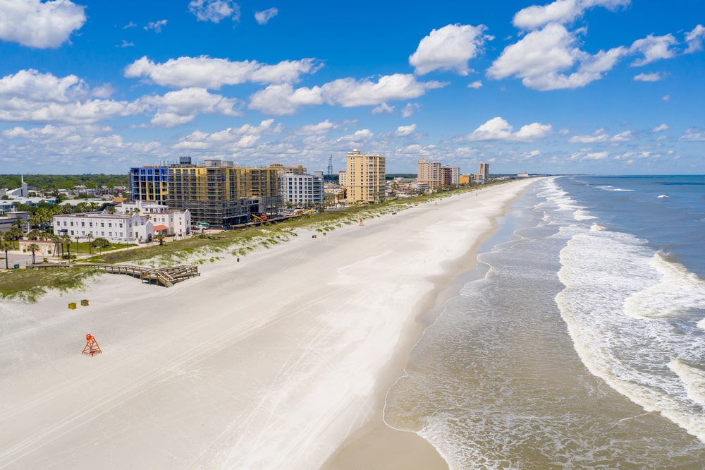 Aerial shot of Jacksonville beach, empty sand, blue sky with clouds