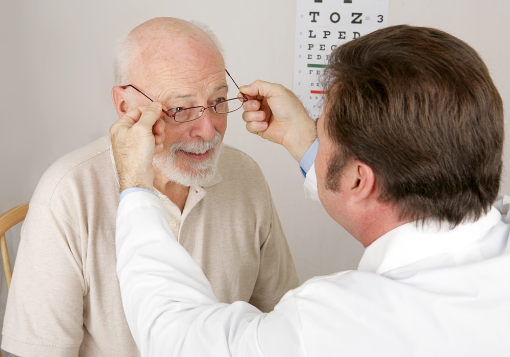 Eye doctor placing glasses on senior man