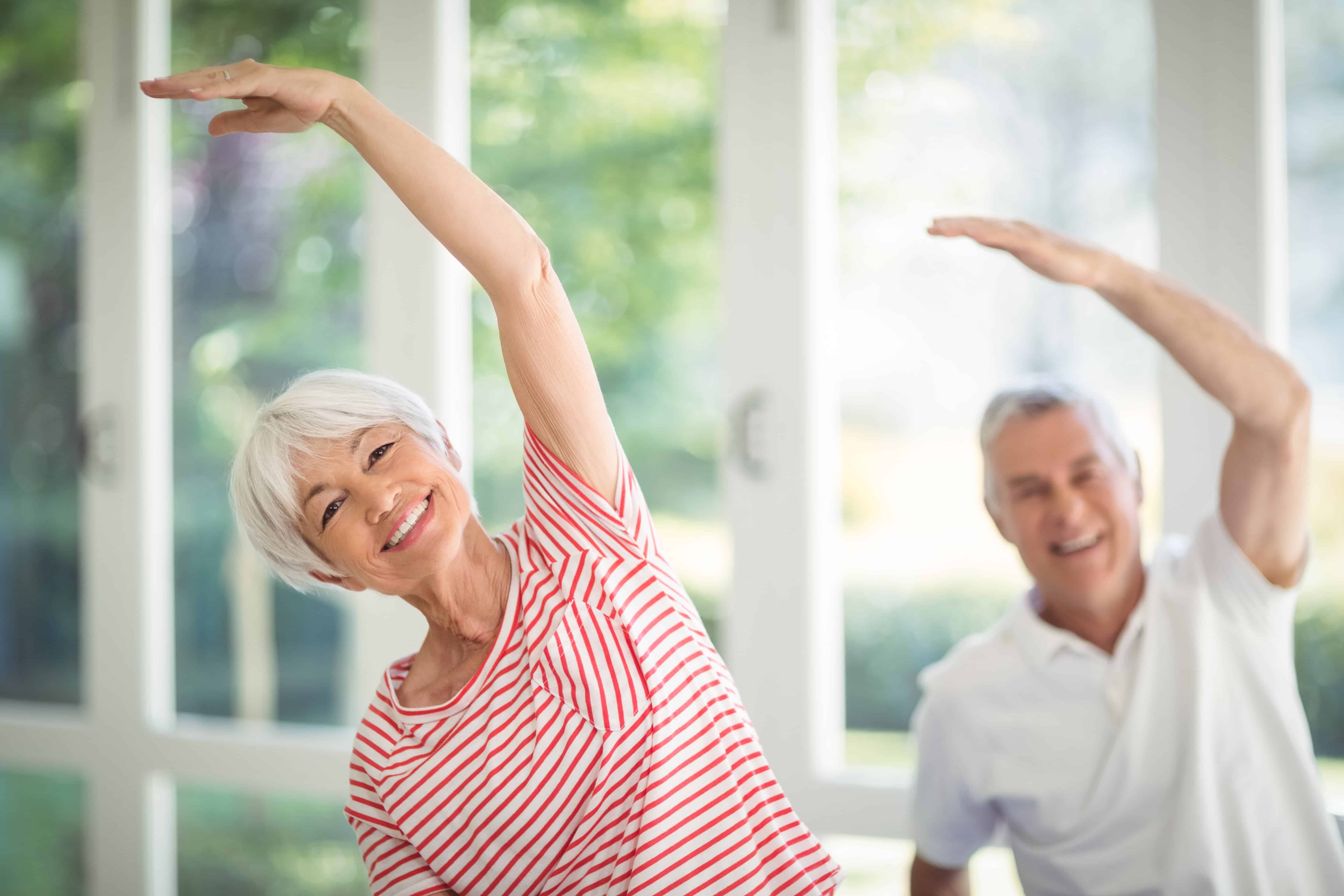 Senior couple smiling and stretching indoors