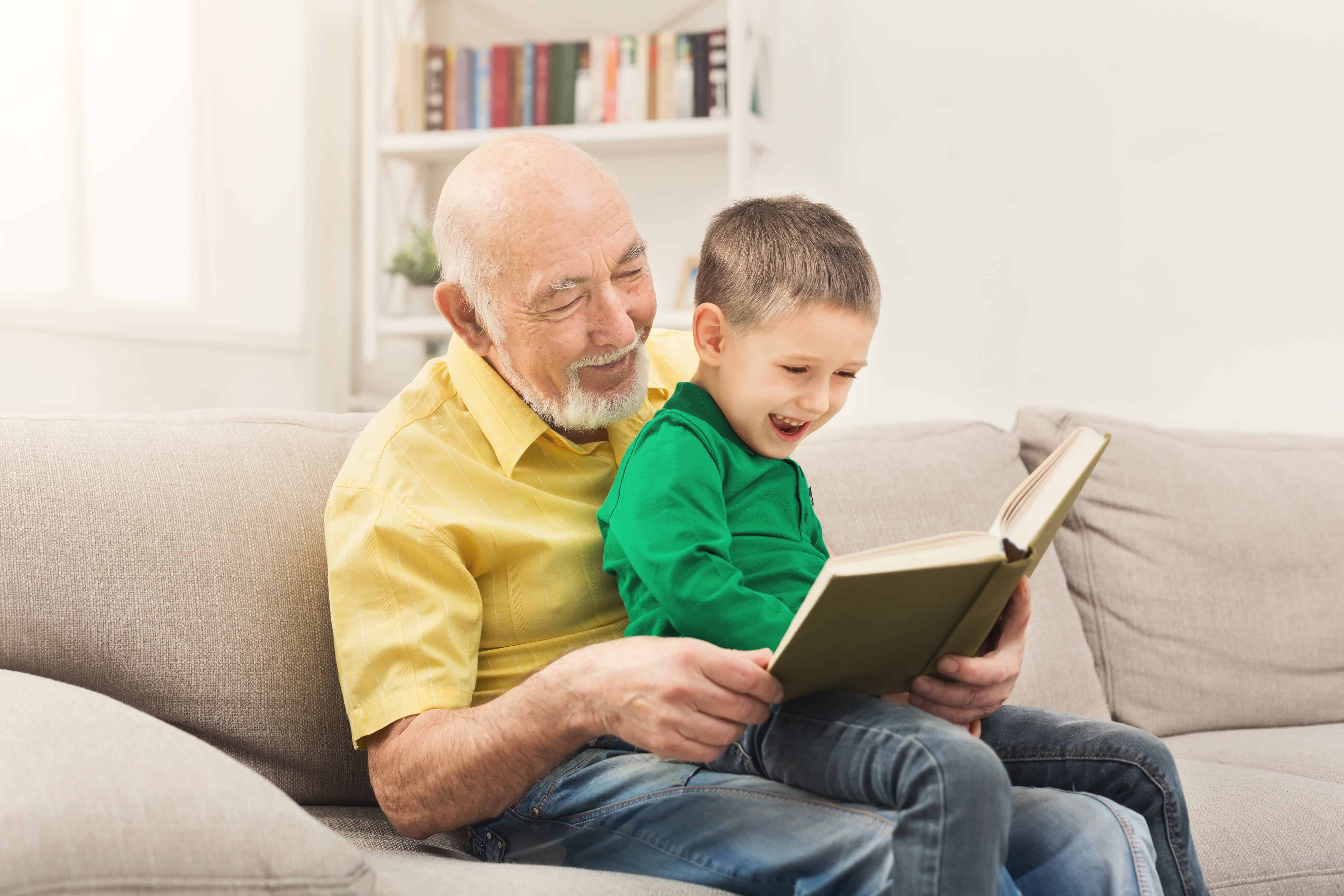 smiling grandpa and grandson looking at book