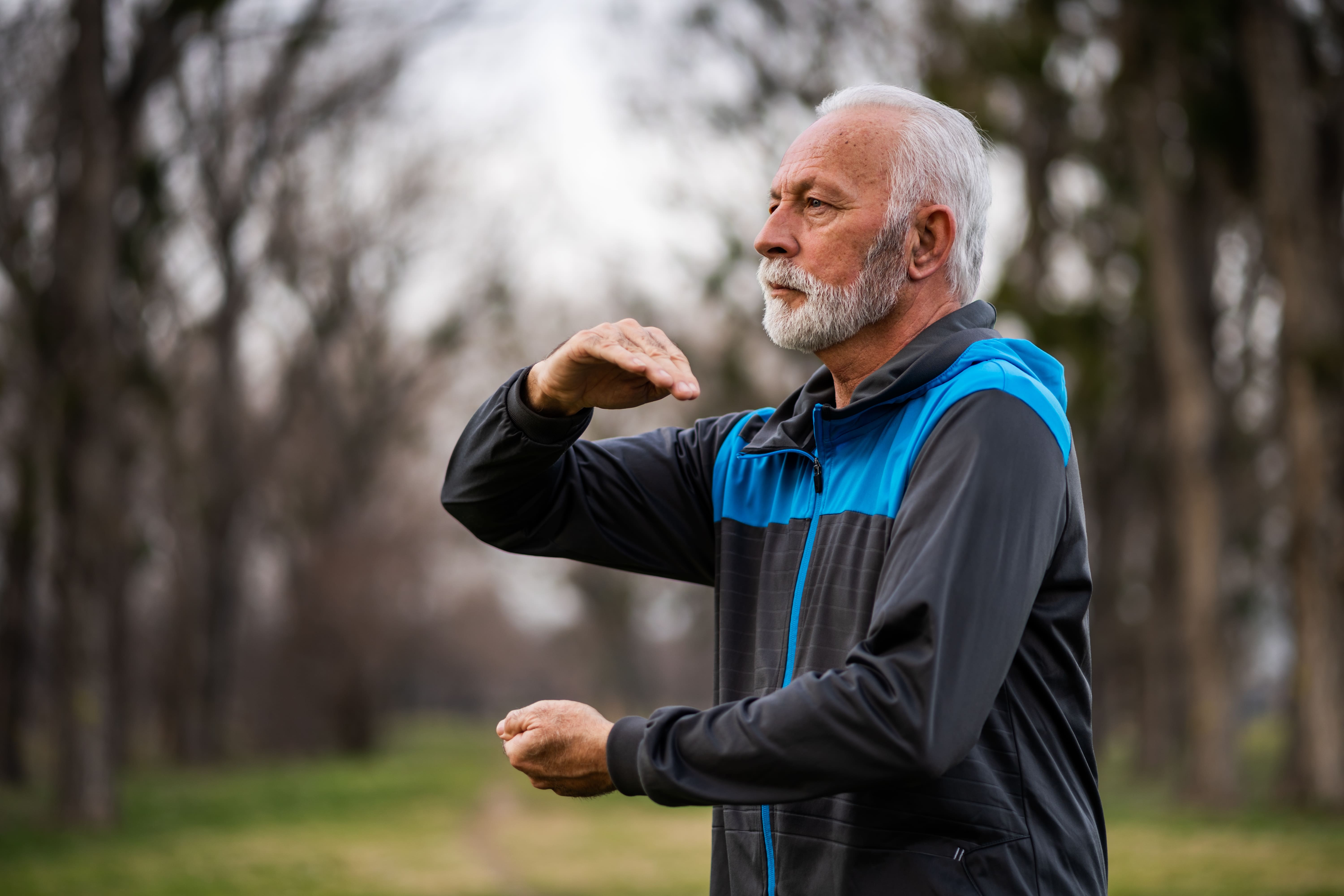 Senior man practicing qi gong or tai chi outside